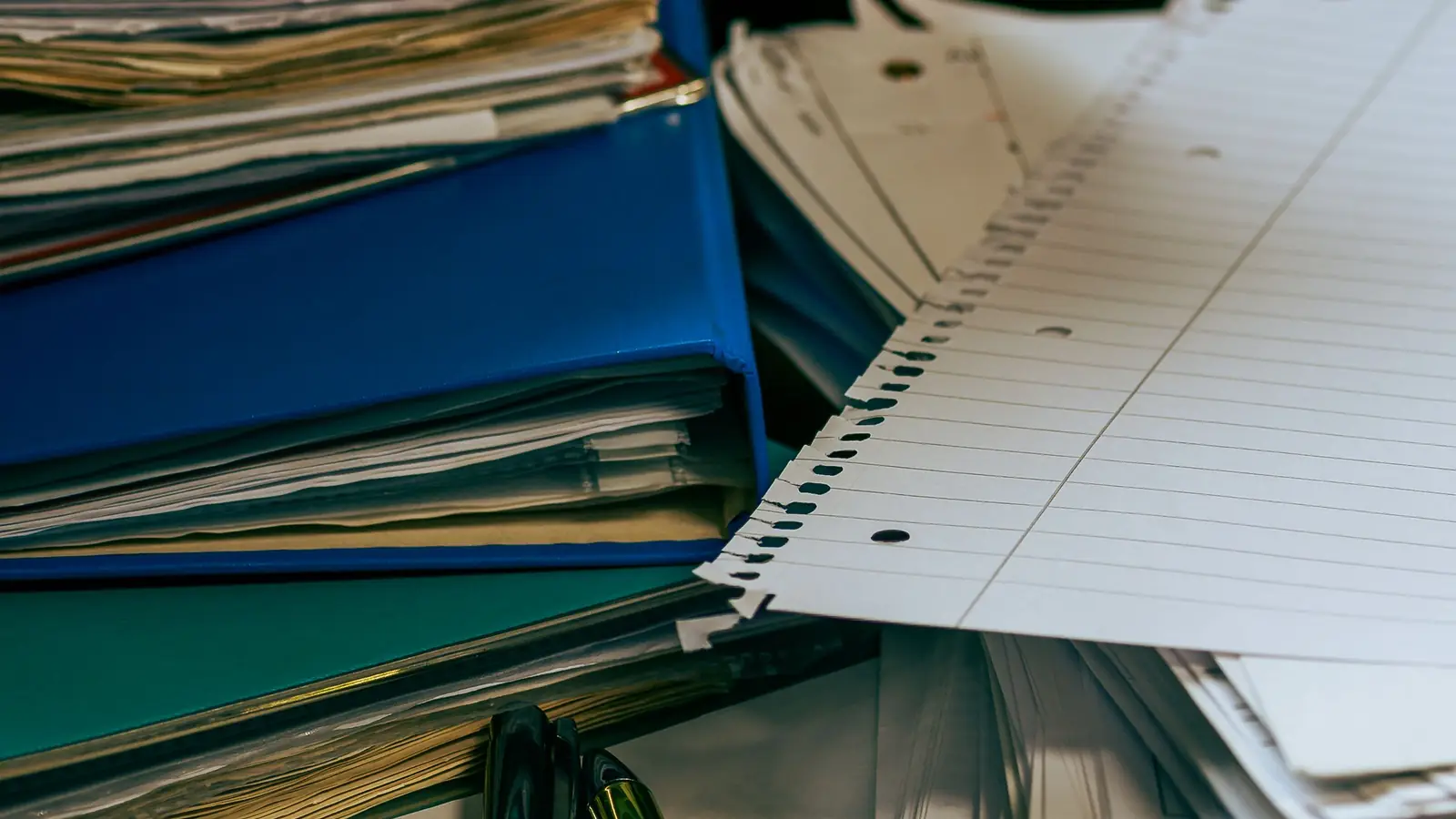 Carpetas y documentos apilados en primer plano sobre una mesa